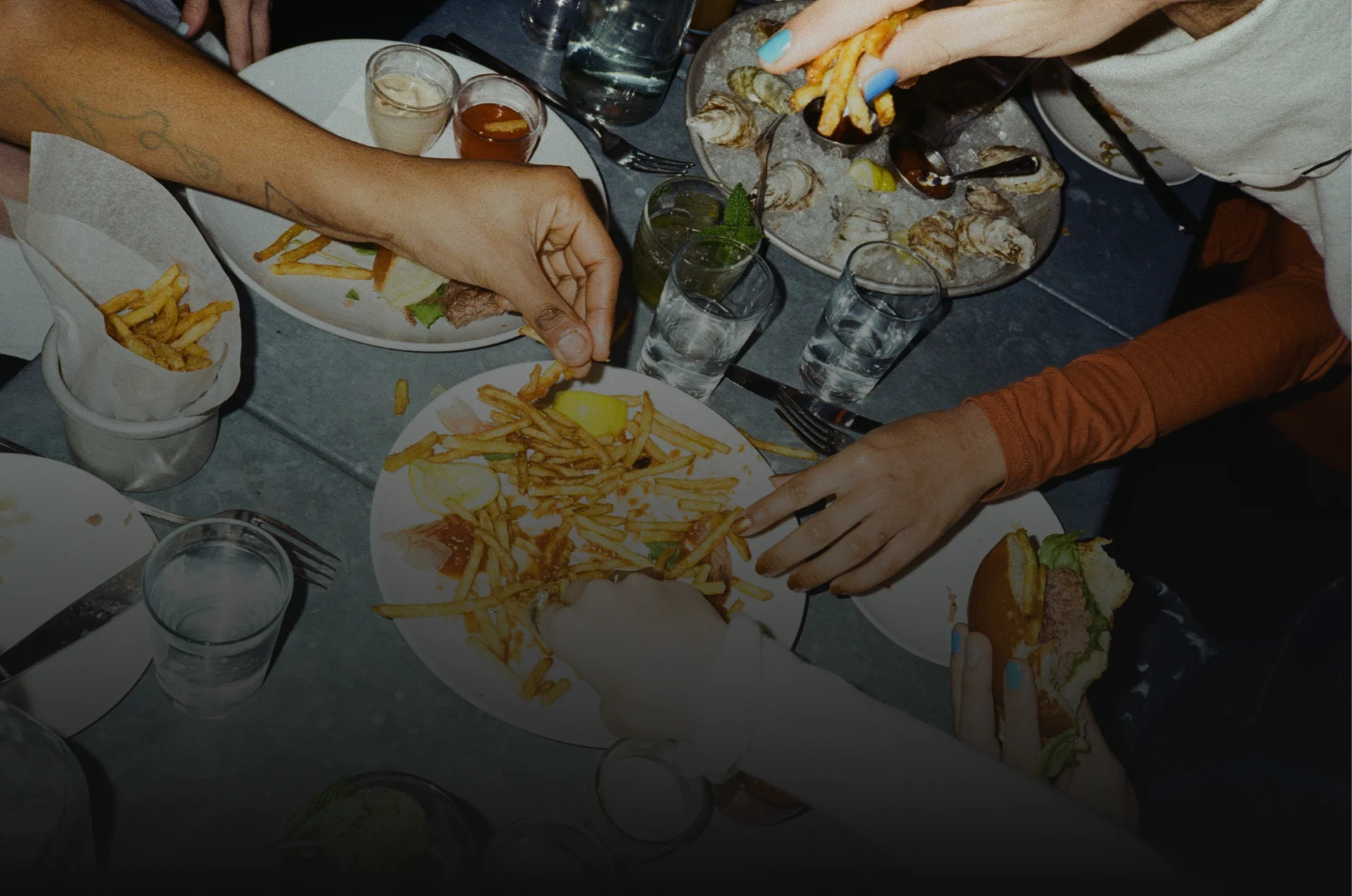 Friends sharing fries, oysters, and drinks around a restaurant table